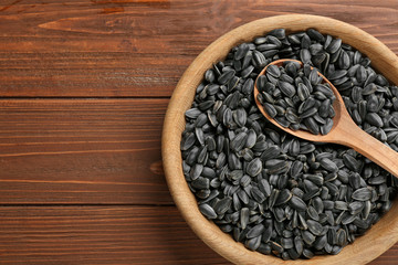 Bowl and spoon with sunflower seeds on table, top view