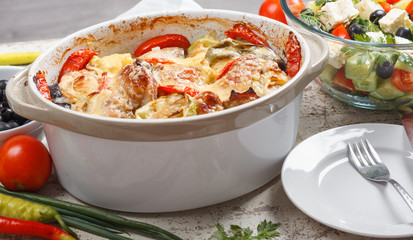 Traditional tasty rustic stew of chicken and vegetables  with Greek salad and black olives
