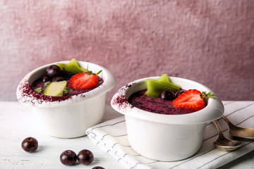 Bowls with tasty acai smoothie on light table