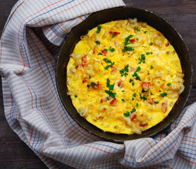 Traditional rustic omelette with bacon, pasta and greens .  Copy space