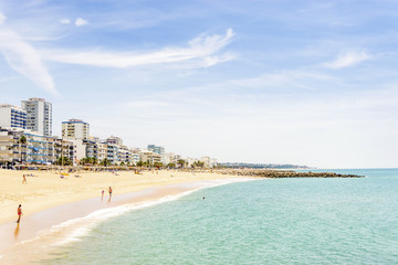 People walking along seaside in Quarteira during sunny day, Algarve, Portugal