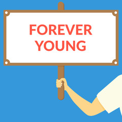 FOREVER YOUNG. Hand holding wooden sign