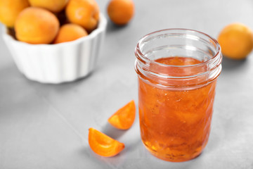 Jar with tasty apricot jam on table