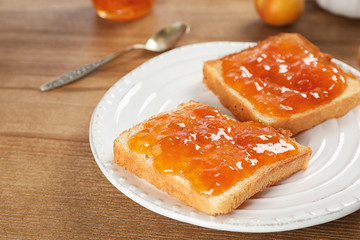 Bread with tasty apricot jam on plate