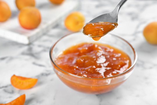 Bowl and spoon with tasty apricot jam on table