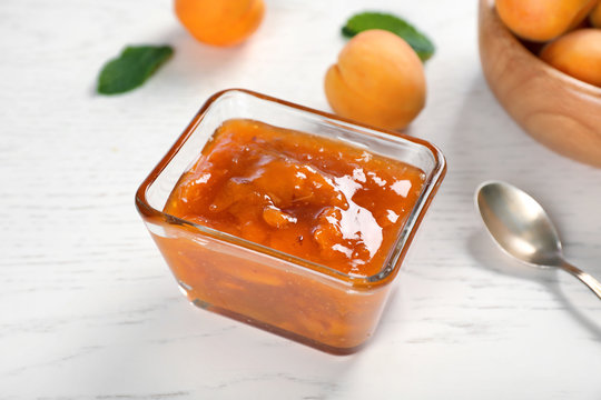 Bowl with tasty apricot jam on table