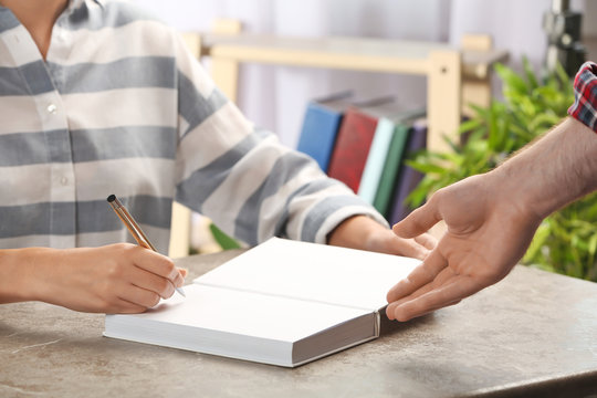 Writer signing autograph in book at table, closeup