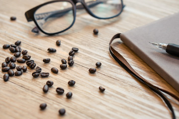 Closeup Coffee beans on the table with glasses and notebook