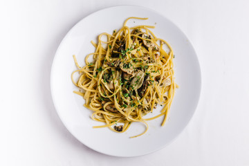Top view of Oyster spaghetti served in white plate on white tablecloth.