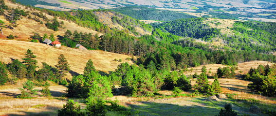Beautiful panorama view from viewpoint.Landscape of Divcibare mountain in west Serbia with golden fields and green conifers,old houses. Europe