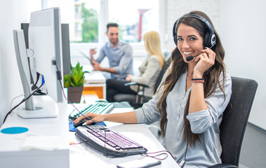 Portrait of happy smiling female customer support phone operator at workplace. - obrazy, fototapety, plakaty