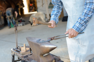 Closeup of farrier striking horsehoe