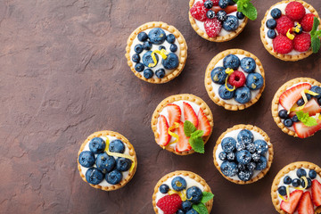 Summer tartlets or cake with cream cheese and mixed berry top view. Tasty pastry desserts. - obrazy, fototapety, plakaty