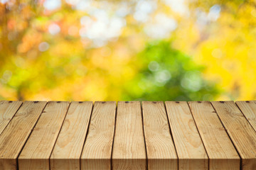 Naklejka na ściany i meble Empty wooden table over autumn nature bokeh background