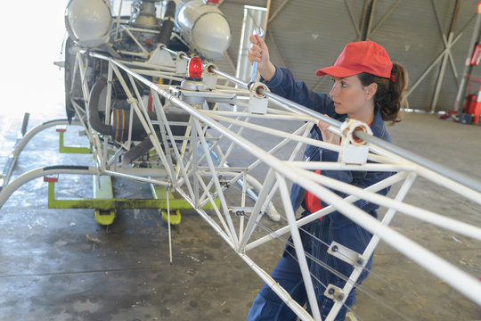 woman checking flying machine in hangar
