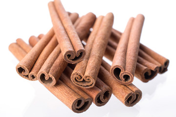 Heap of dry cinnamon sticks on white background