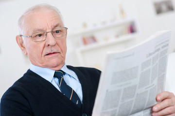 elderly man reading at a newspaper