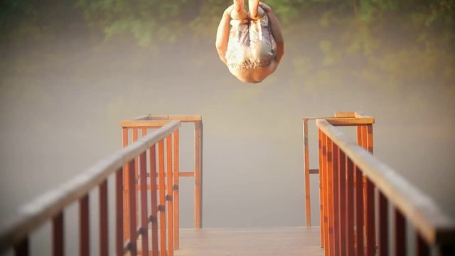 Seminuded man doing backflip jumping on the bridge