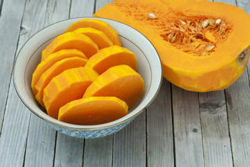 a bowl of sliced pumpkins on old table