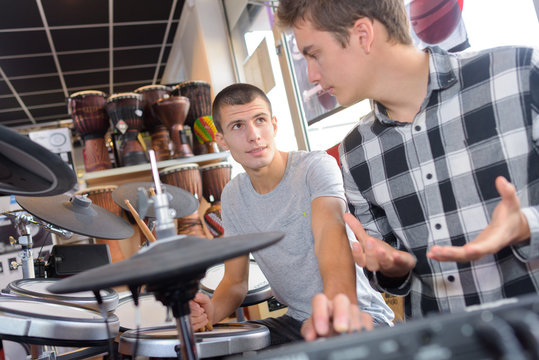 2 teens looking at drums in music store