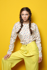 Fashion portrait of young elegant woman in studio. Yellow background