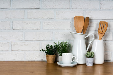 There are various cookers on the table, background made of bricks painted white color only. It feels a homelike atmosphere looking a tidy table in the kitchen.