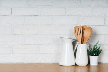 There are various cookers on the table, background made of bricks painted white color only. It feels a homelike atmosphere looking a tidy table in the kitchen.