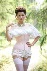 beautiful young chubby girl posing in medieval retro corset and white vintage lingerie in the forest