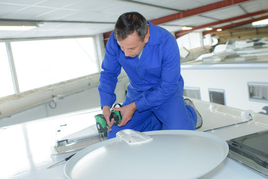 Mechanic using cordless drill on roof of camper van