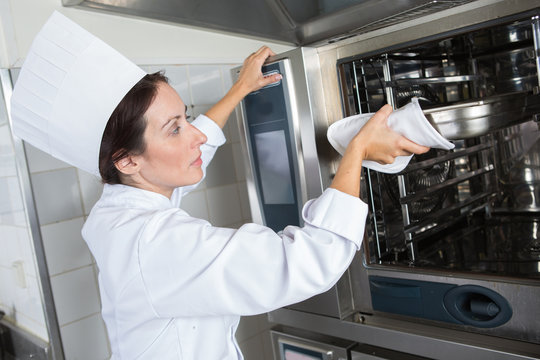 female chef putting something in industrial oven