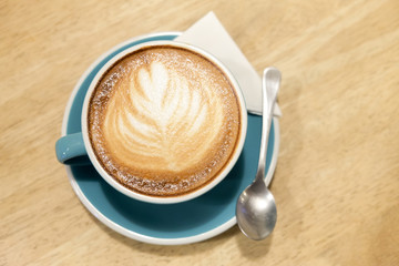 A cup of coffee Latte art green glass on wood table