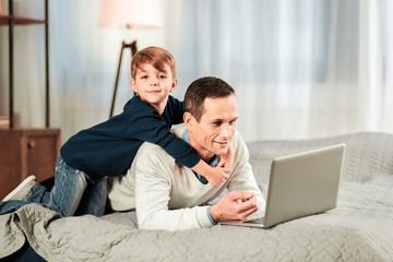 Cute child. Pleasant nice boy looking at you while hugging his father