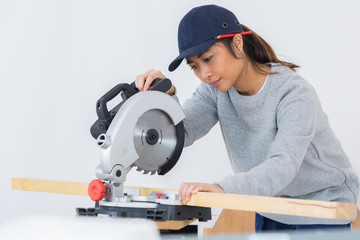 female carpenter is using a circular saw