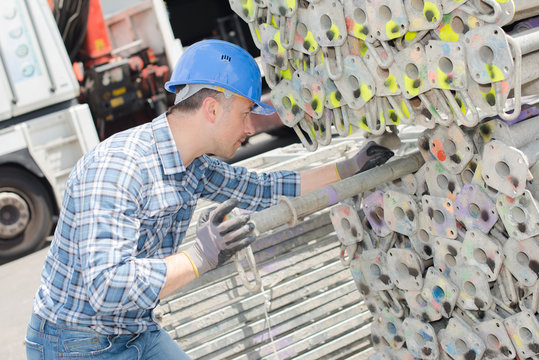Worker selecting scaffolding pole from stack