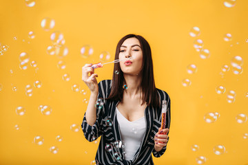 Woman with soap bubbles, yellow background