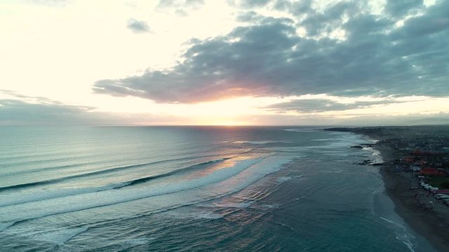 Sunset on the black sand beach, Indonesia, Bali. Aerial view. 4K