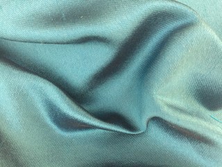Fototapeta premium Woven texture of silk fabric or yarn turquois beige color changeable for background. Draped folded satin.