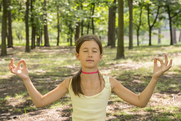 girl's happy and Meditate on the practice of yoga in the park , yoga kid. Healthy lifestyle - little girl doing yoga in the park. Healthy and Yoga Concept