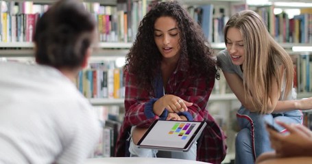 High school students studying together in a library with a digital tablet - Powered by Adobe