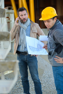 engineer and worker with cell phone on a transformer