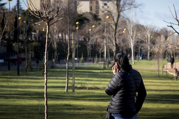 Mujer hablando por teléfono de espaldas en el parque de la ciudad