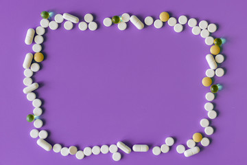 Frame of pills on a purple background. Pills for design. Concept of health, healthy lifestyle. Copy space for advertisement.