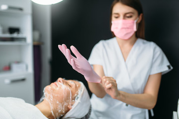 Beautician wears gloves, patient with face mask
