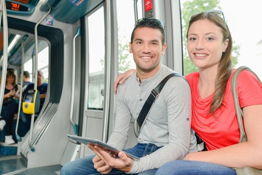 Couple on public transport holding tablet
