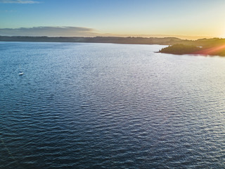 Rupanco Lake, one of the Great lakes in Southern Chile with an amazing aerial view from the drone over Osorno and Puntiagudo Volcanoes surrounded by the water and the trees during the sunset, Chile