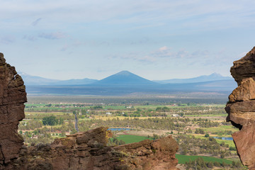 Blac Butte volcano seen from Smith Rock trail, with pine trees and rocks in Oregon, USA © Em Campos