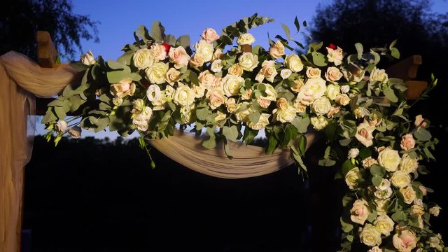 Closeup view of beautiful place made with wooden square and floral pastel decorations for outside wedding ceremony in wood. Real time video footage.