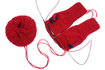 A red red thread and knitting gloves isolated on white background. View from above.