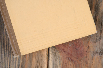 A book in yellow binding on a wooden background. View from above.