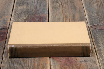 A book in yellow binding on a wooden background. Front view.
